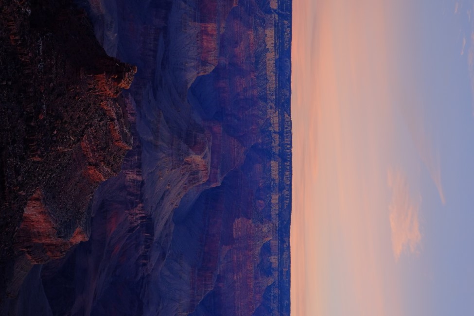 the grand canyon at sunrise. the dim morning light casts a blue tinge over the red rock walls.